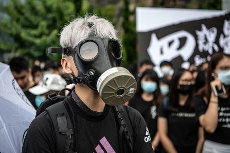 Hong Kong protester wearing CBRN gas mask for tear gas protection during civil unrest - chemical crowd control agent defense