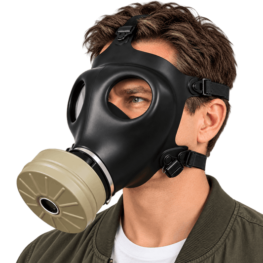 A man wearing a black full-face cbrnmaks.com  gas mask with a beige filter canister, photographed against a clean white background.